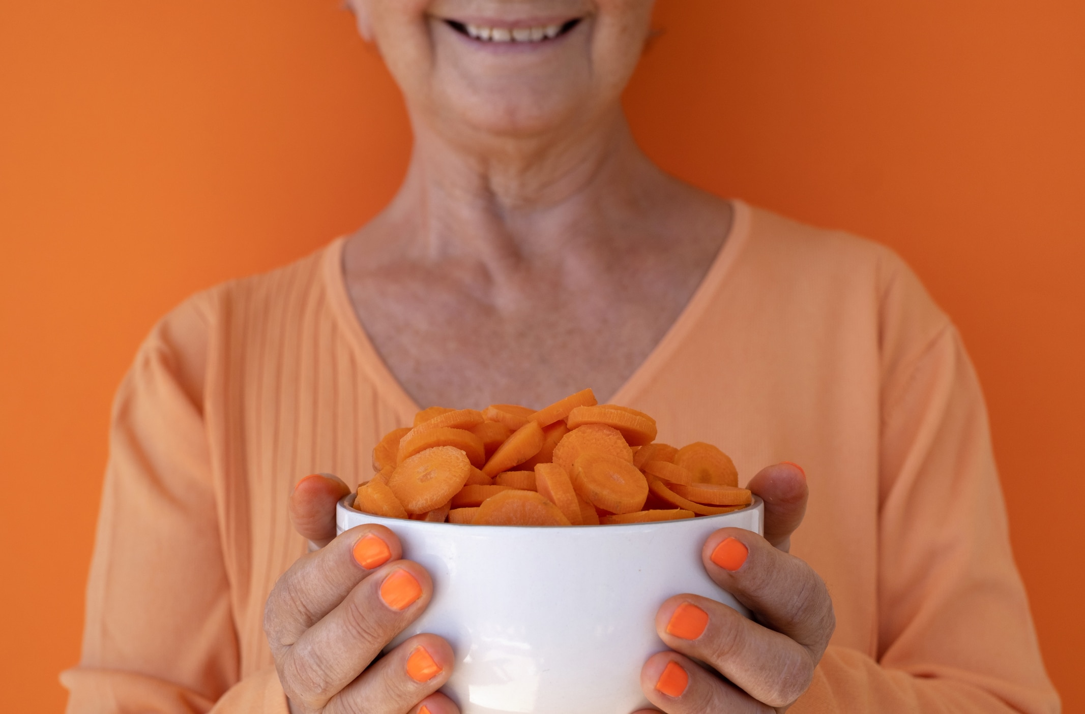 a person holding a bowl of carrots