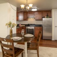 Modern Kitchen With A Cozy Dining Area, Featuring A Round Table With Elegant Table Settings, Showcasing The Inviting Living Space At One Lincoln Park.